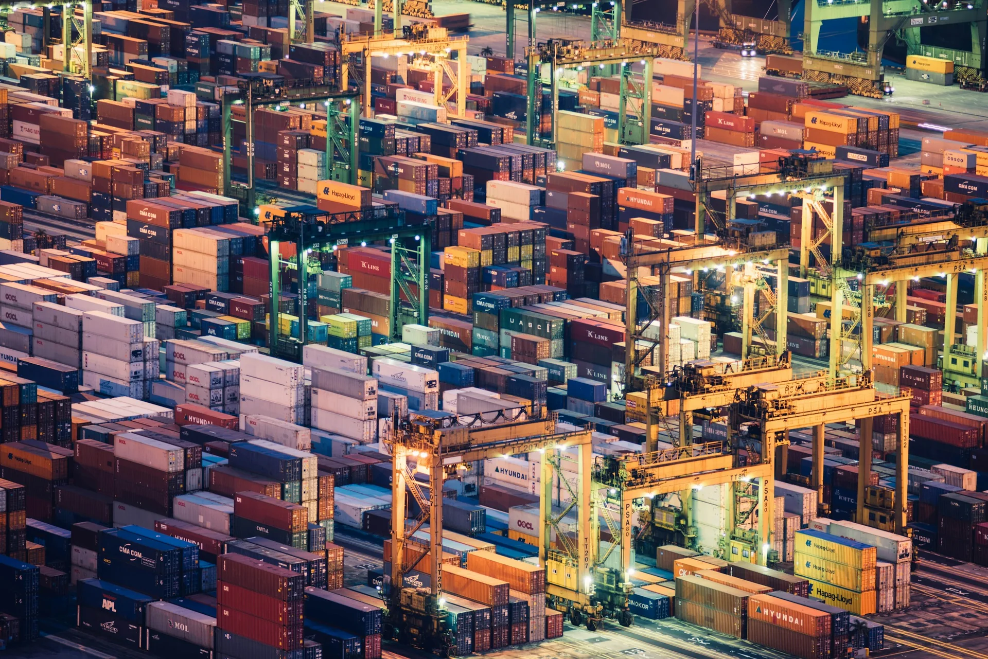Aerial view of organized shipping containers and roadways at a container terminal.